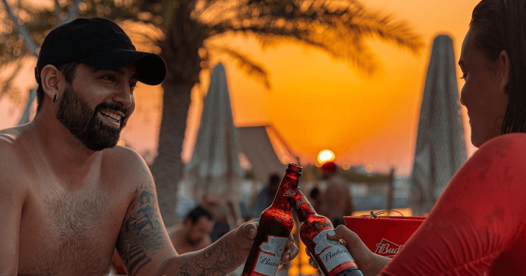 Two guest toasting their drinks while the sun goes down in the background