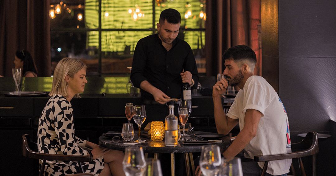 Waiter serving wine to a couple at BABA Steakhouse