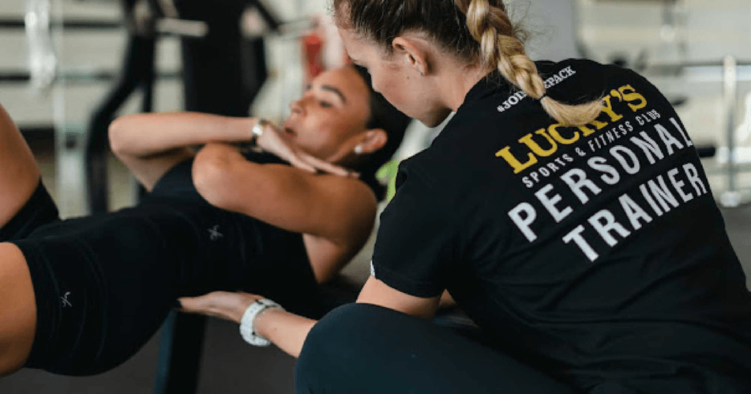 Personal trainer supporting woman doing an exercise.