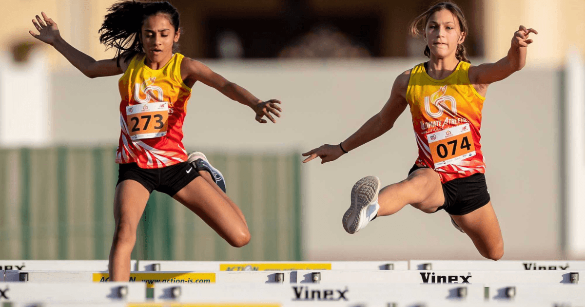 Two girls doing high jumps on an athletics track