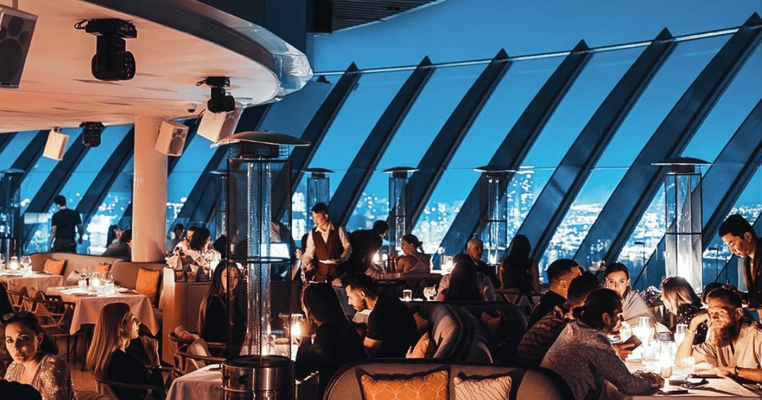 People sitting around tables at a roof top restaurant 