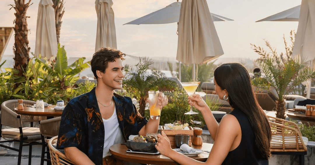 A lady and man sitting at a table enjoying cocktails 