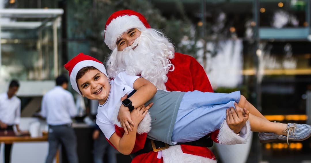 Man dressed at Santa Clause holding a boy