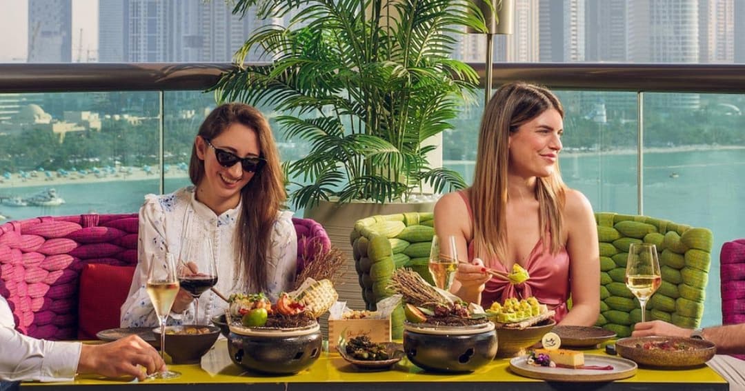 Two ladies eating lunch at a table sea in the background