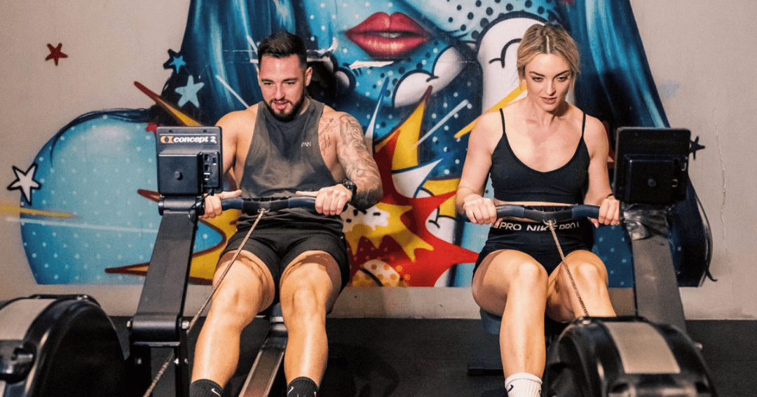 Two people rowing on a rowing machine