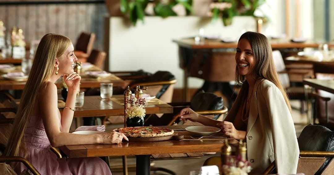 Two women eating a pizza