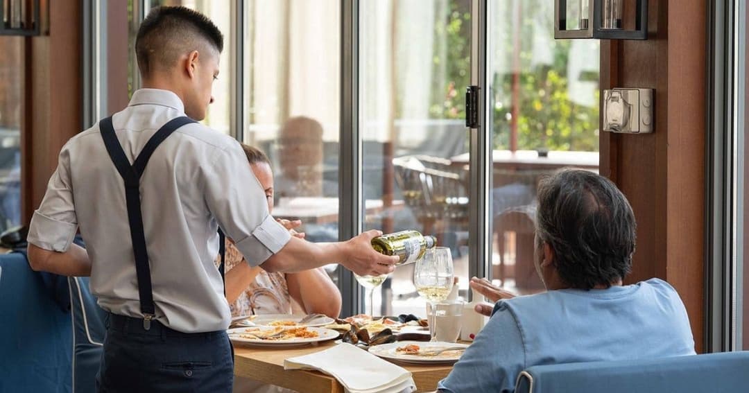 Waiter serving wine to guests