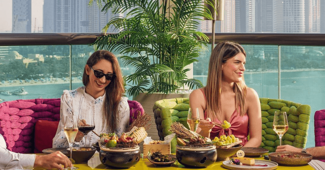 Two women enjoying drinks and food with a view