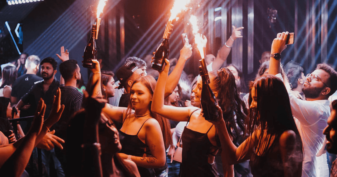 Waiters holding up champagne bottles at a club