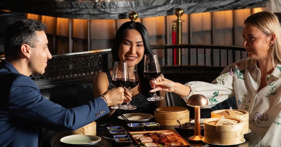 Three people drinking red wine and toasting their glasses 