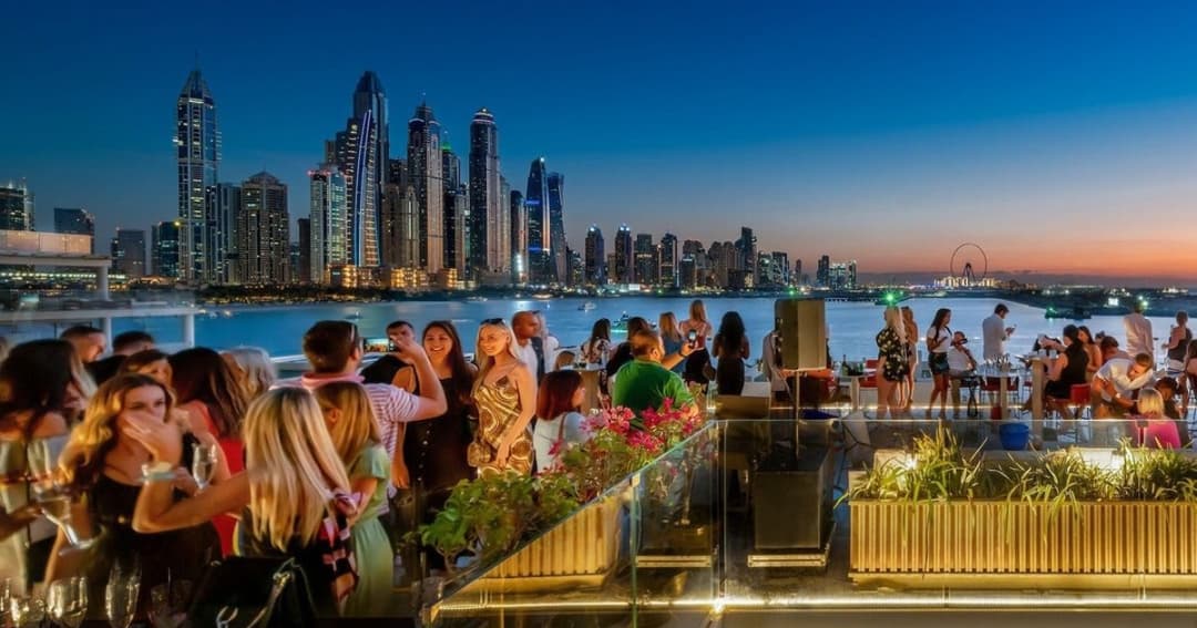 People socialising on a rooftop with Dubai Marina views 