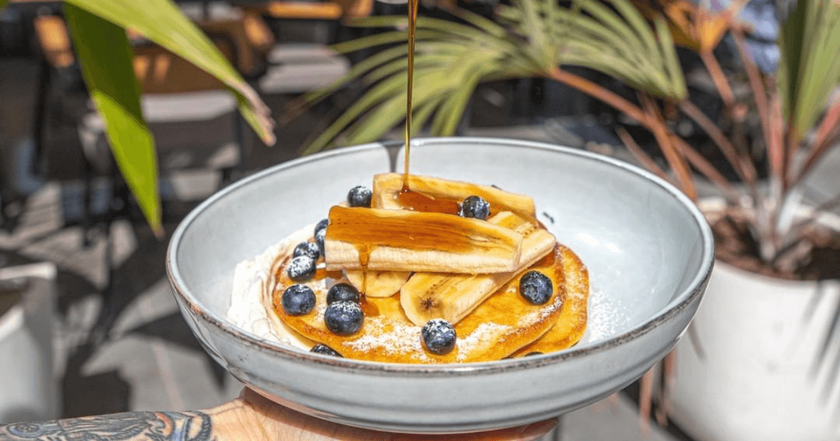 Syrup being poured over pancakes