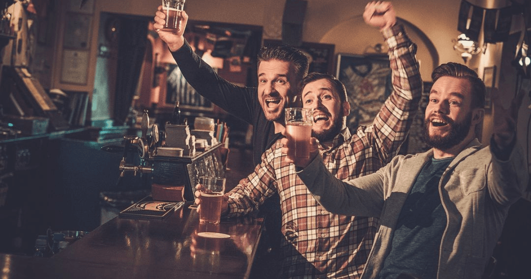 Three men cheering by the bar