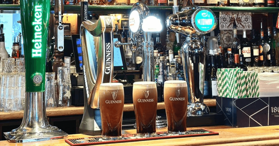 Three pints of Guiness at the bar.