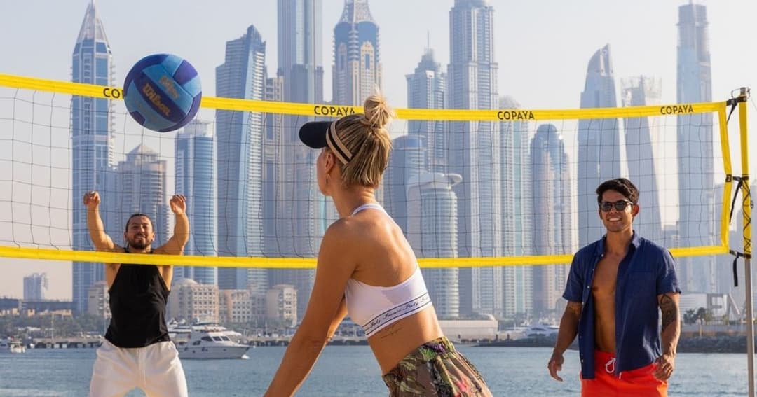 Three people playing volleyball on the beach