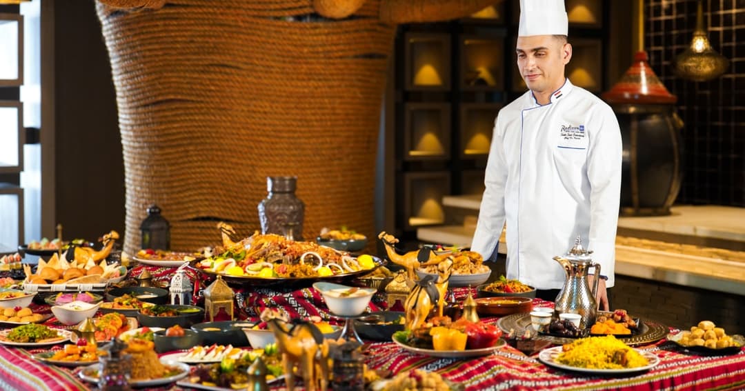 Chef posing in front of many Iftar dishes