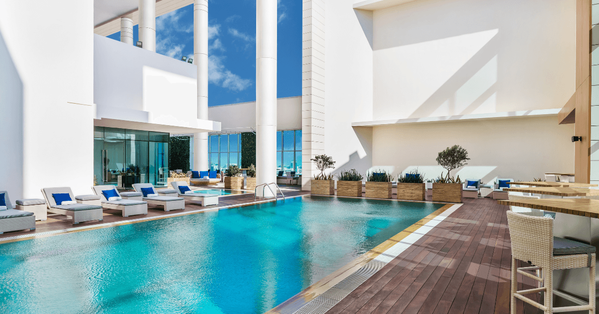 A rooftop pool with sun loungers and tables 