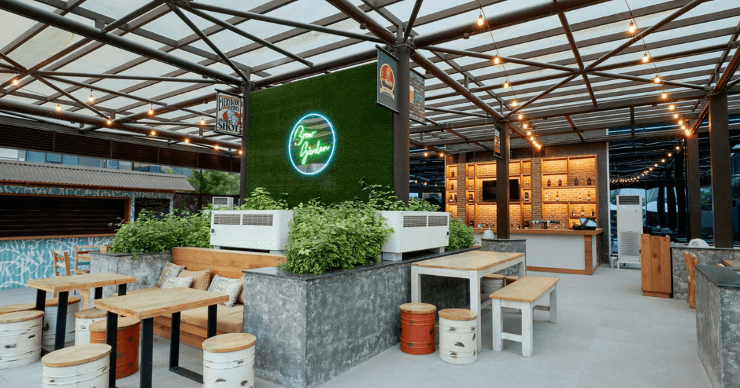 Modern outdoor seating area at Brew House in Dubai with neon signage and greenery.