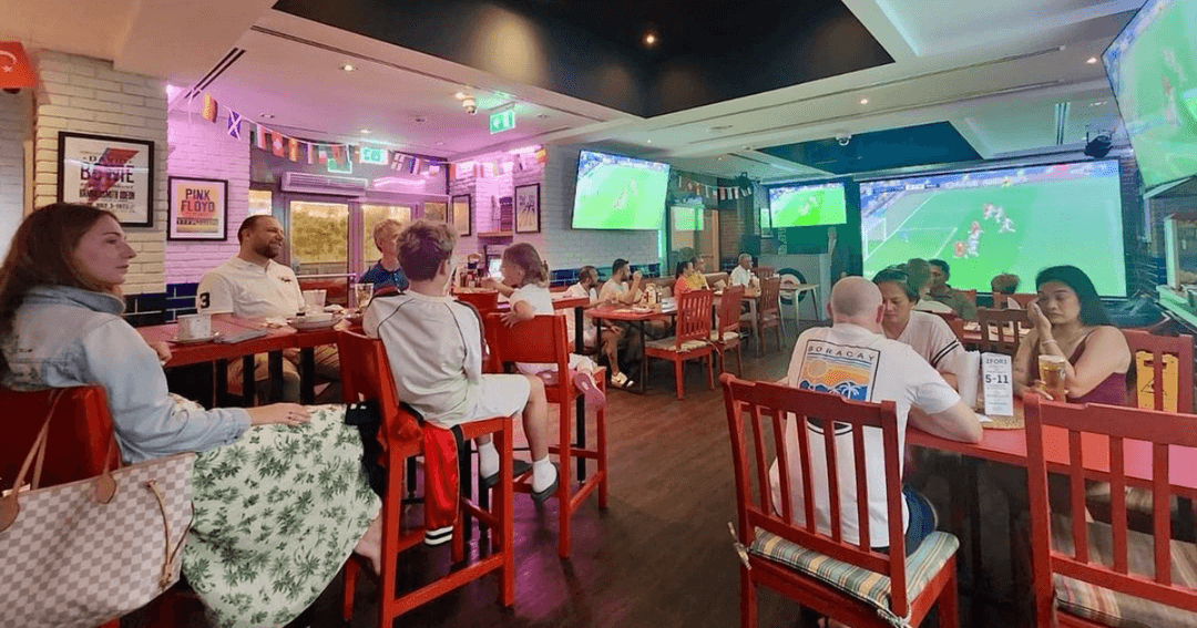 People watching sports (Euros 2024) on multiple screens at Brighton Rock in Dubai, enjoying a lively atmosphere.