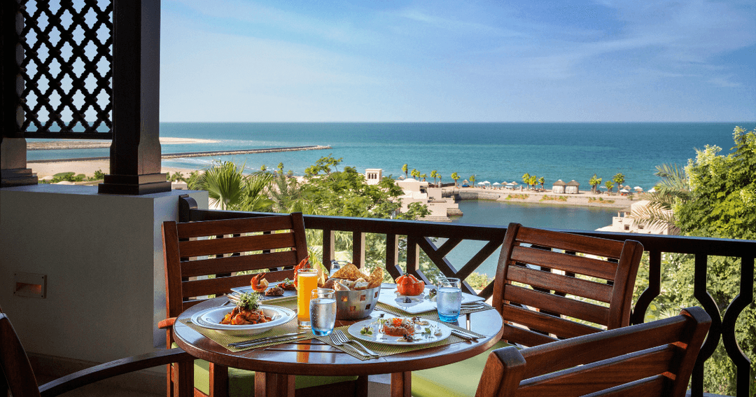 Scenic dining experience at The Cove Rotana Resort in Ras Al Khaimah with a breathtaking view of the sea, featuring a table set with a delicious meal.