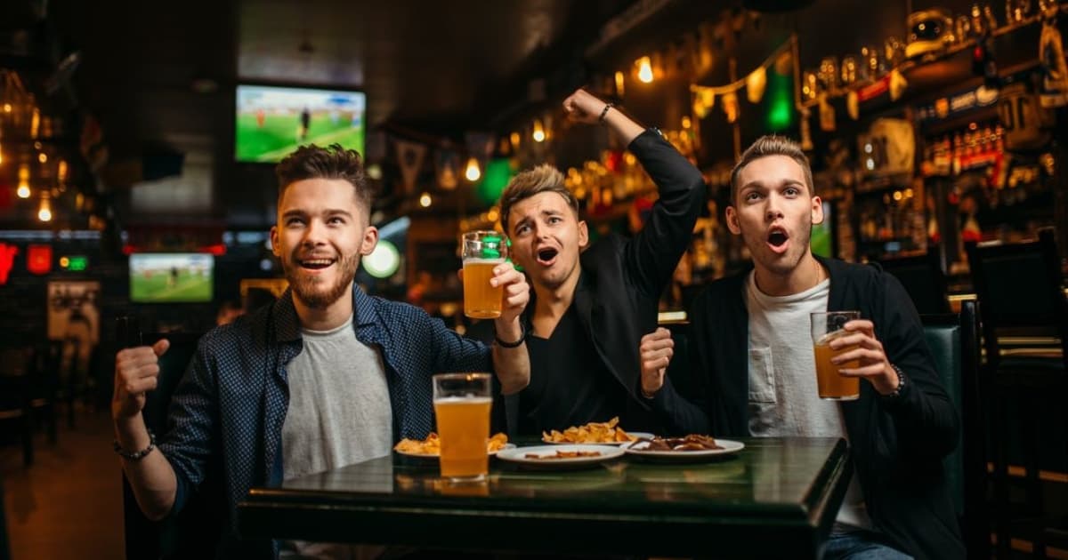 Excited group of friends cheering at Harvester's Dubai during a thrilling 2024 Euros game.