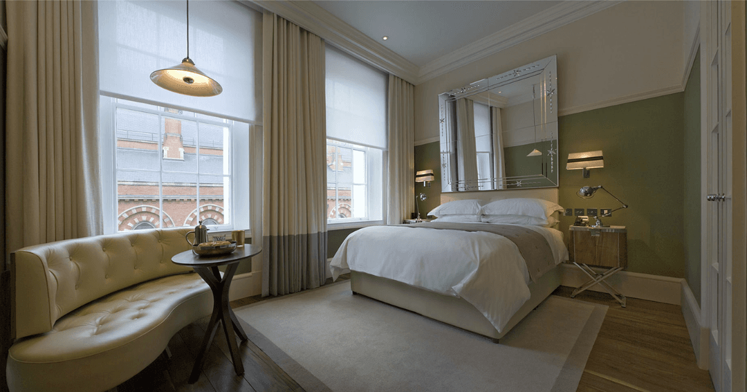 A beautifully designed bedroom at The Great Northern Hotel in London, with modern furnishings, large windows, and a cozy seating area.