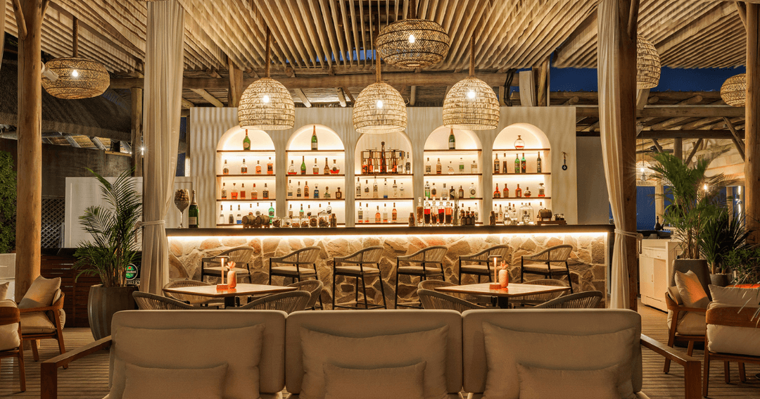 Elegant interior of Laguna Beach Taverna's bar area in Dubai, featuring stylish lighting and a well-stocked bar.