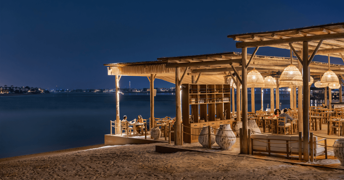 Scenic waterfront dining at Laguna Beach Taverna in Dubai, with tables overlooking the water and ambient evening lighting