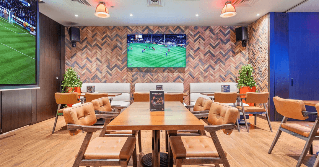 Cozy seating area with large screens for sports viewing at The Huddle Sports Bar & Grill in Dubai.