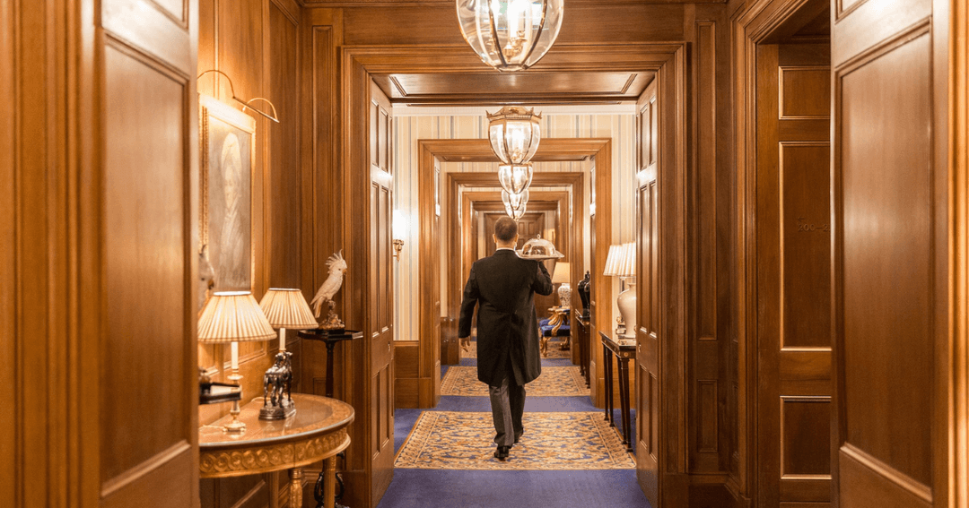 Butler carrying a tray in the opulent hallway of The Lanesborough London.