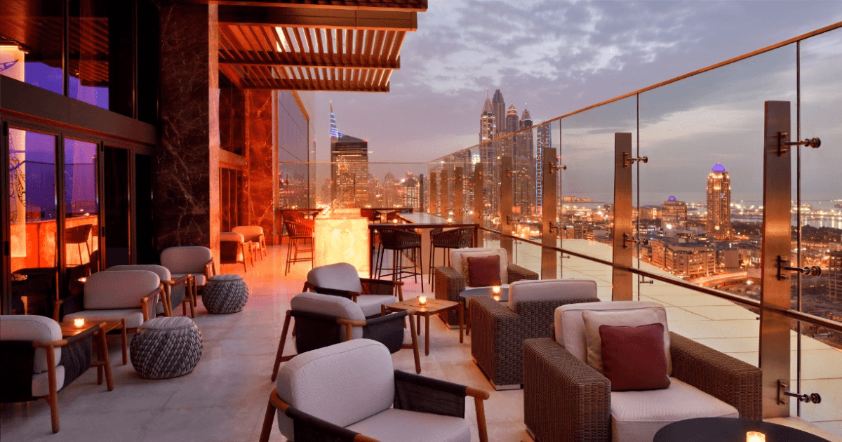 A stunning rooftop view at TwentyThree Dubai, offering cozy seating and breathtaking skyline vistas at dusk.