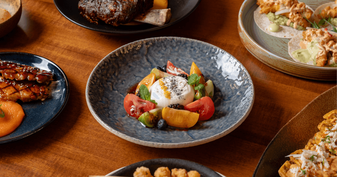 A delicious spread of diverse dishes at ZOCO Dubai, showcasing a delightful burrata salad surrounded by fresh heirloom tomatoes and vibrant garnishes.