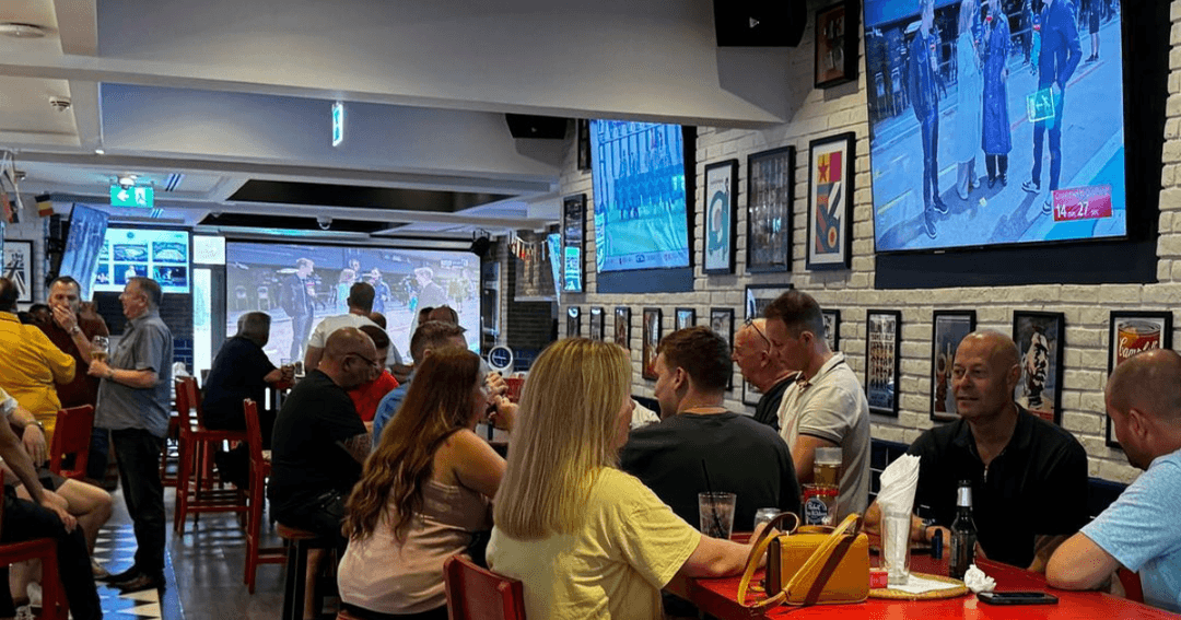 Patrons watching sports on multiple screens at Brighton Rock, a cozy sports bar with a vibrant atmosphere.