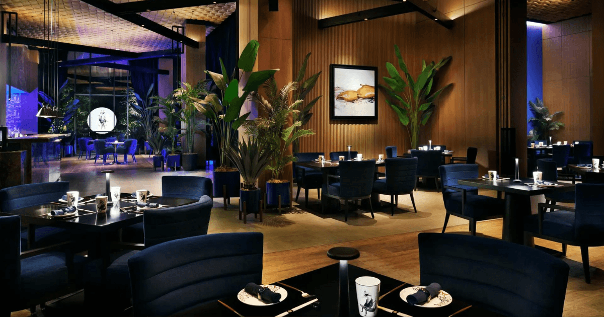 Chic and modern interior of Demon Duck restaurant, featuring elegant dining tables and lush greenery at Banyan Tree, Bluewaters Dubai