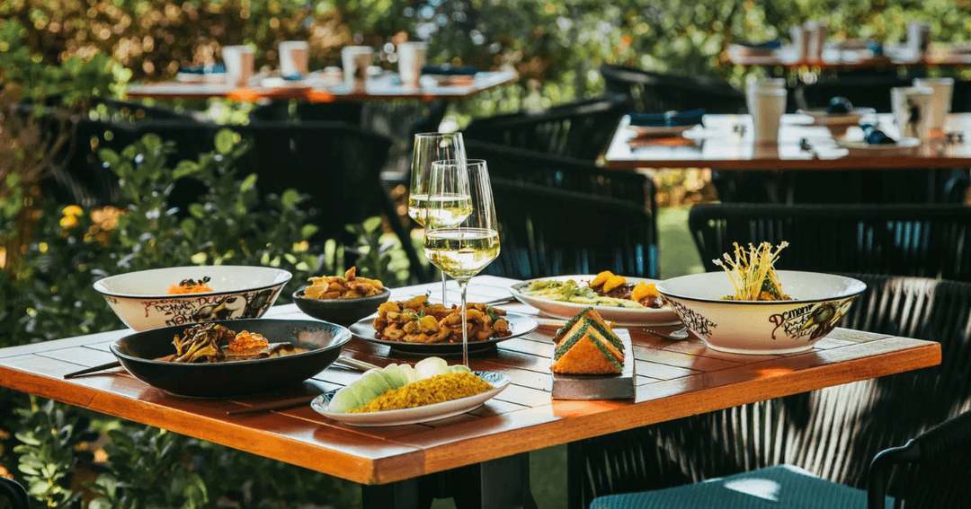 Outdoor dining setup with an array of Asian dishes at Demon Duck, Banyan Tree, Bluewaters Dubai