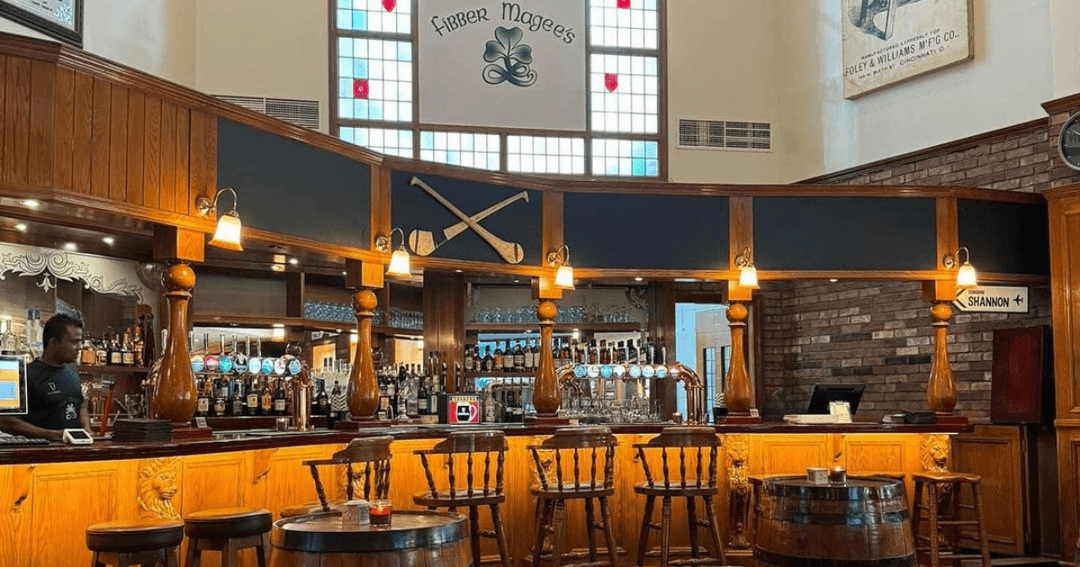 The wooden bar counter at Fibbers, Dubai, featuring traditional Irish decor and a variety of drinks.