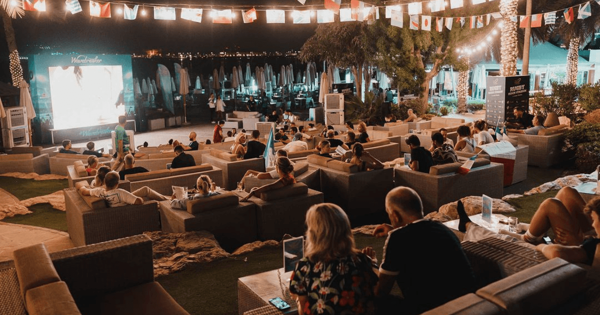 Guests enjoying an outdoor movie screening on large couches at Main, Dubai, with a cozy and relaxed setting.