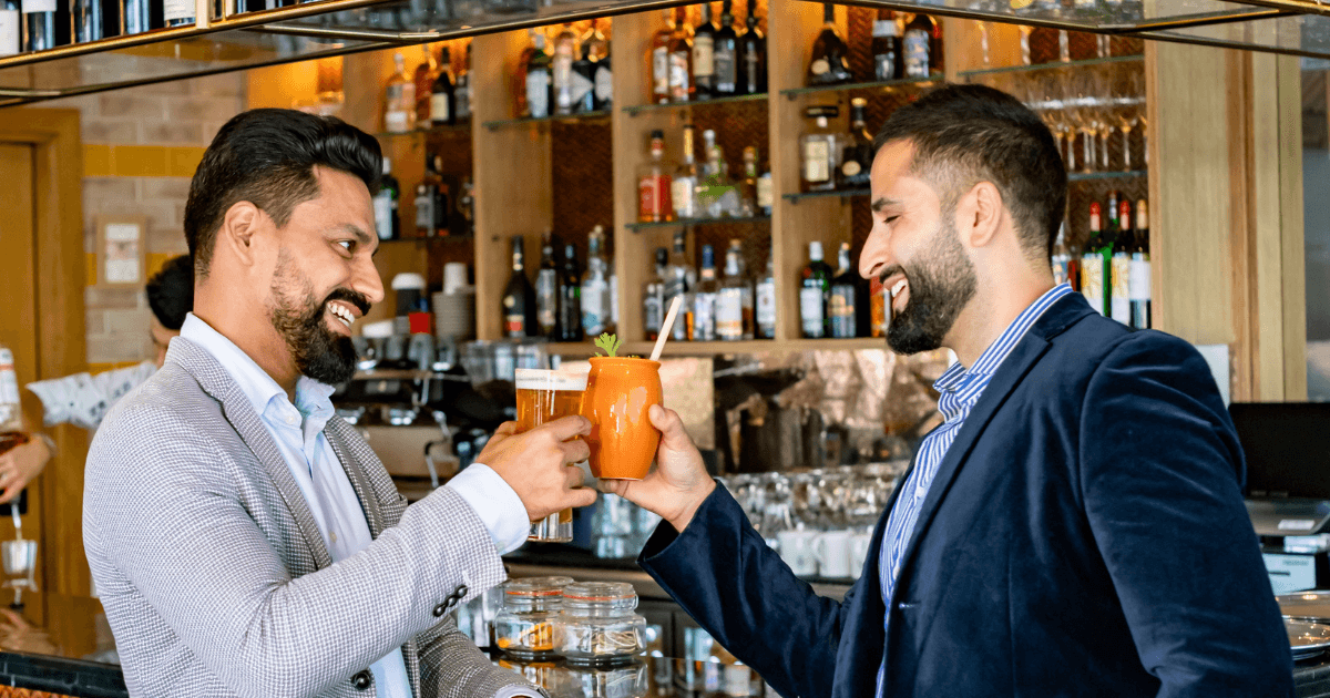 two men toasting their drinks by the bar